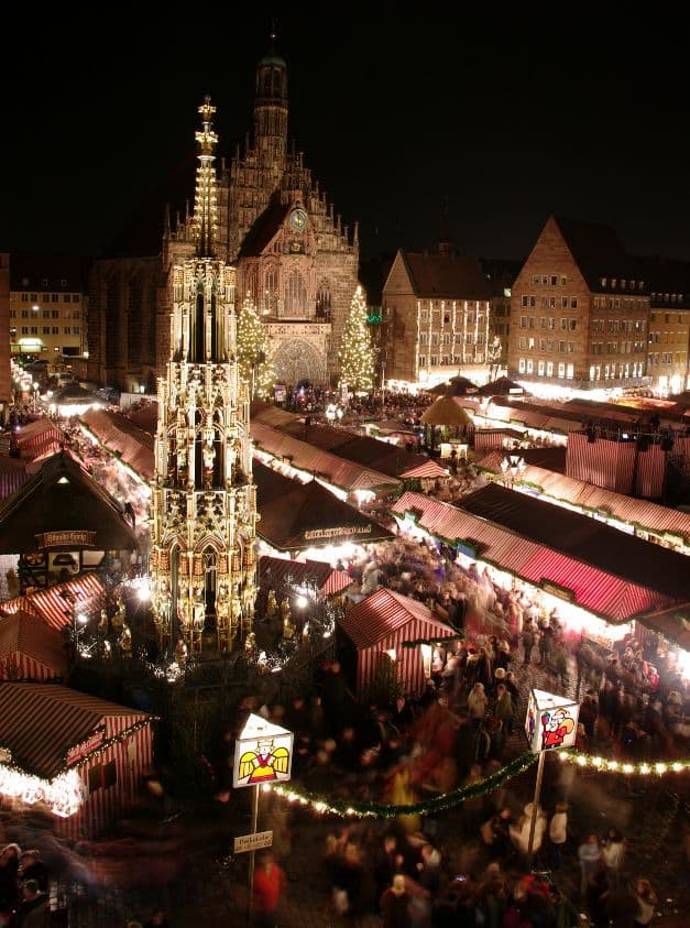 A glowing Christmas market at night in Vienna with wooden stalls, warm lights and a church behind