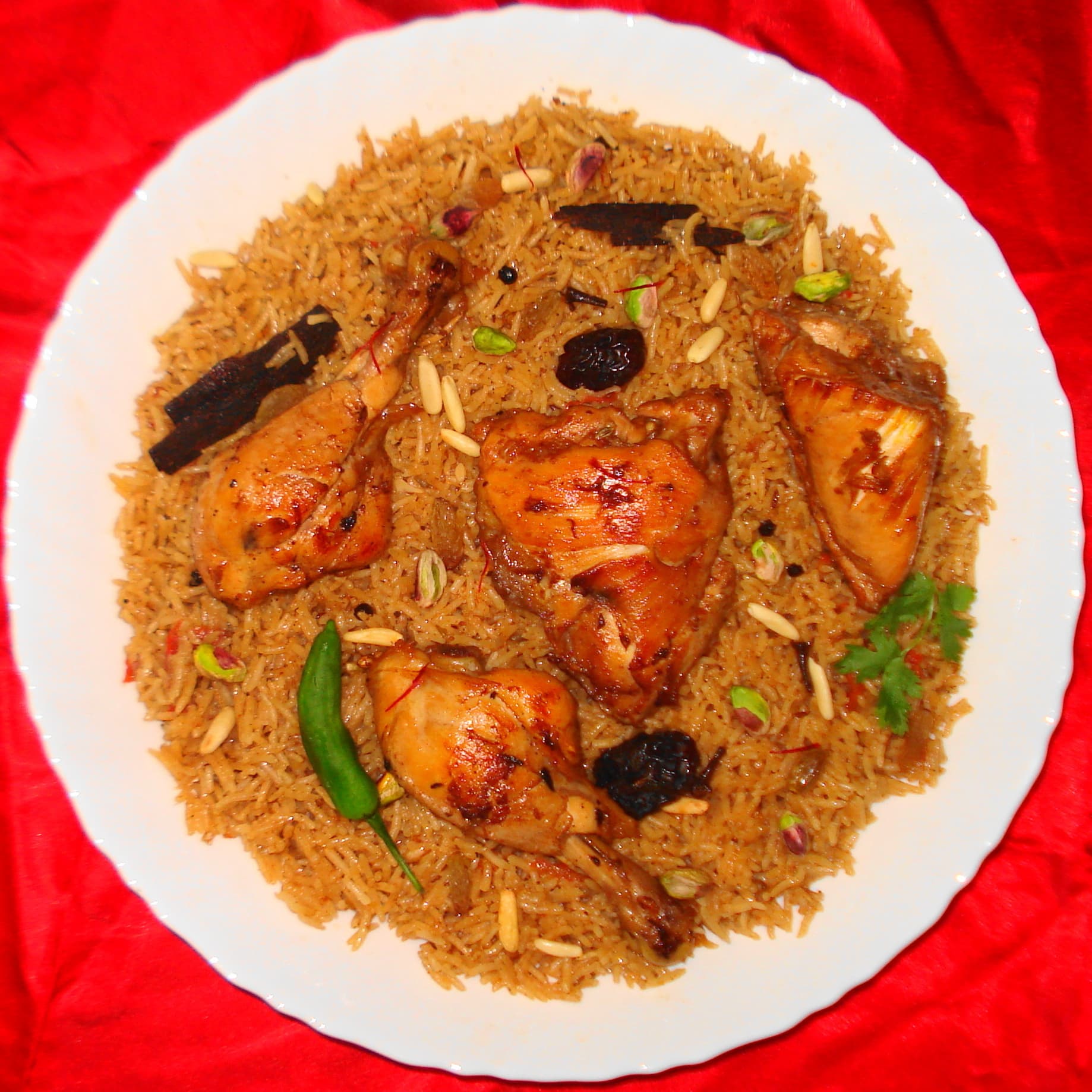 A large platter of golden machbous rice topped with tender meat and garnished with fried onions